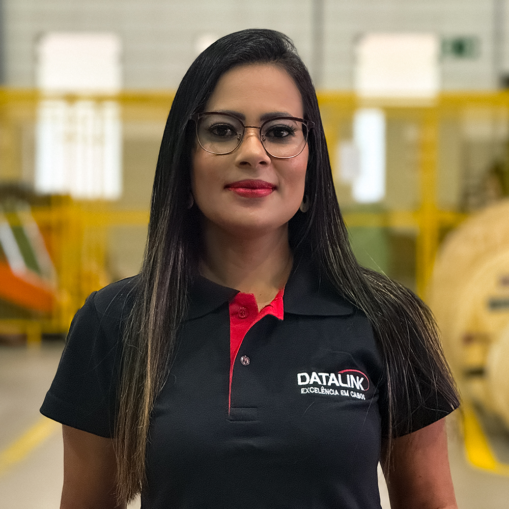 Cindy Esta imagem mostra nossa vendendora Cindy dos Santos vestindo uma camisa polo preta e vermelha com o logotipo “Datalink, Tecnologia em cabos”, em um fundo branco.