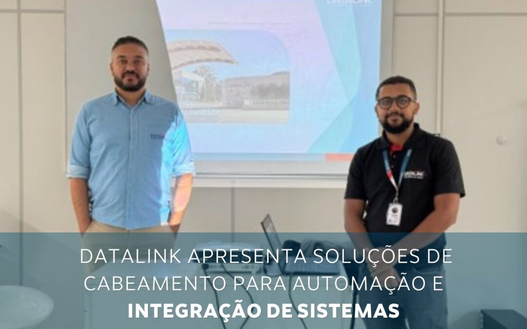 Two men in a meeting room stand in front of a projector displaying a slide about Datalink's cabling solutions for automation and system integration.