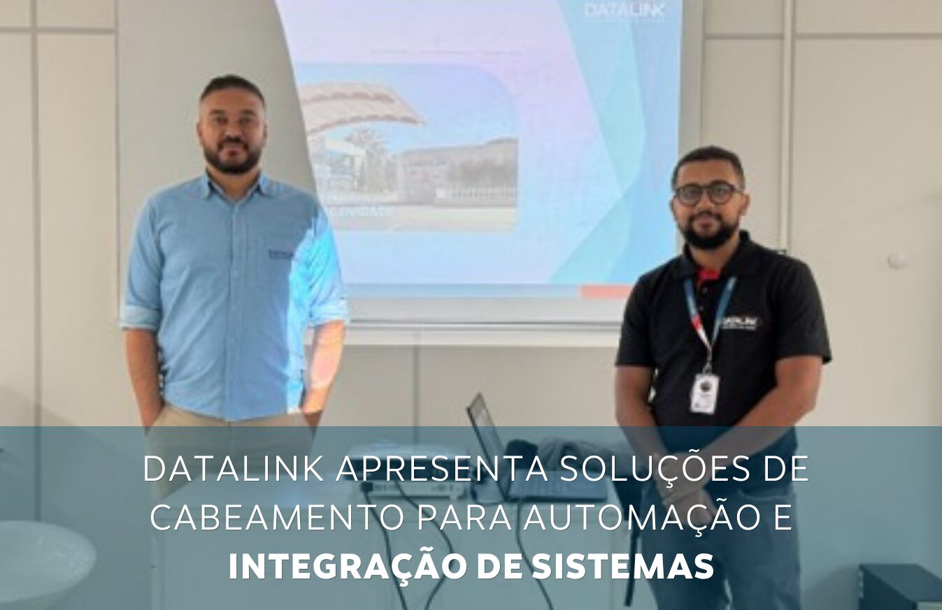 Two men in a meeting room stand in front of a projector displaying a slide about Datalink's cabling solutions for automation and system integration.